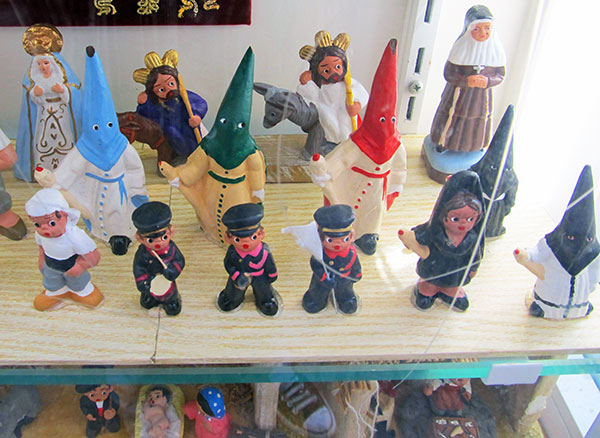 nazarenos among statuettes in a seville old town storefront 