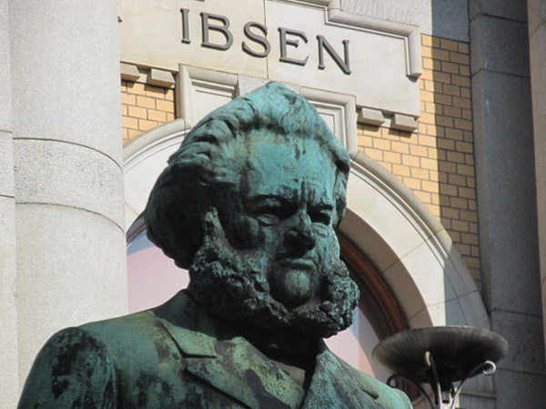statue of henrik ibsen in front on national theatre in oslo, norway